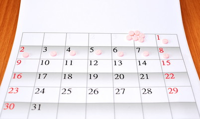 clean sheet monthly calendar with period admission handful tablet on wooden table