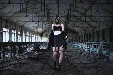 Beautiful, young girl post apocalypse girl stand in abandoned factory with gas mask