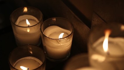 Closeup of many burning candles in darkness in interior. Real time full hd video footage.