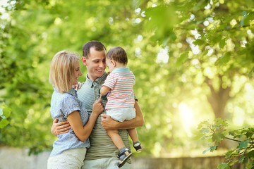 Happy young family walking in summer park. Mother father and little child son play in nature.