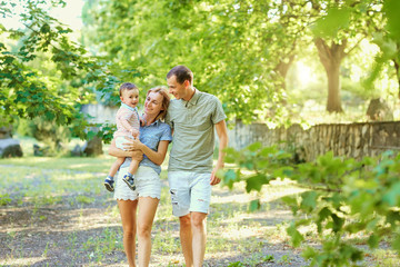 Fototapeta premium Happy young family walking in summer park. Mother father and little child son play in nature.