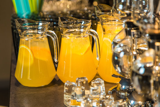 Elegant orange drinks with slices of orange fruit inside big glass bowls and blurry vacuum glass siphons in foreground. Drinks served on table ready for holiday celebration. Horizontal color photo.