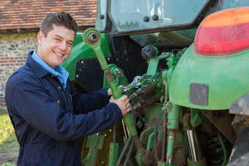 Obraz premium Portrait Of Mechanic Repairing Tractor On Farm