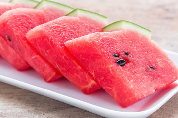 Watermelon is cut into pieces in a white dish.