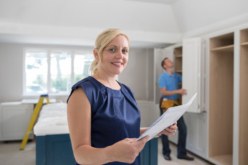 Portrait Of Woman Looking At Plans For New Luxury Kitchen