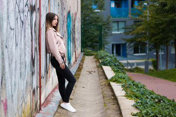 Portrait of informal fashionable girl on graffiti wall background