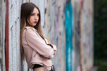 Naklejka premium Portrait of informal fashionable girl on graffiti wall background