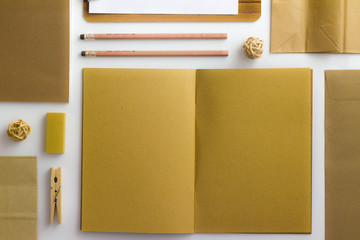 Top view of white table with pencil, notebook, brown paper ,paper bag and clipboard