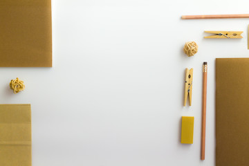 Top view of white table with pencil, notebook, brown paper and paper bag