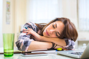 Exhausted young woman sleeping at desk.