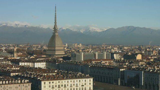 Town center view of Turin with the Mole Antonelliana major landmark building on the left in a sunny morning in autumn with the snowy mountains in the background
