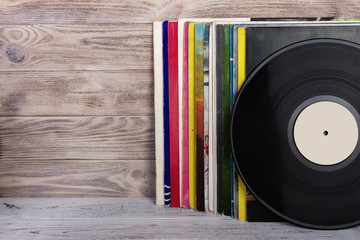 Retro styled image of a collection of old vinyl record lp's with sleeves on a wooden background....