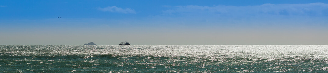 Ilha e barco no horizonte.