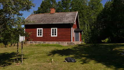 Mähroboter mäht Wiese vor schwedischem Ferienhaus