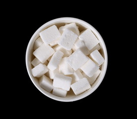 White sugar cubes in bowl isolated on black background and texture
