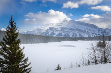 Beautiful Mountain Landscape with a Frozen Lake in Foreground during a Snowfall. 