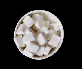 White sugar cubes in bowl isolated on black background and texture