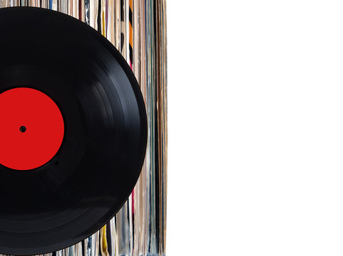 Black record with red label and pile of many close standing vinyl records in old color covers on left side on photo over white background studio shot front view closeup