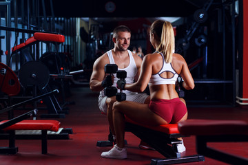 Fitness couple exercising with weights in the gym.