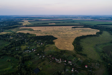 Panoramic view of the valley with green fresh fields and village. Aerial view of countryside with beautiful lake