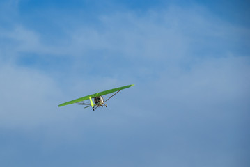 A flying hang-glider with a motor on the background of a blue sky, a view from below