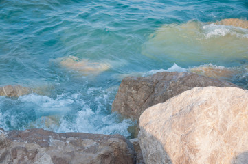 Sea waves and stones on sunny afternoon