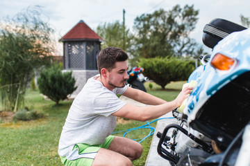 Naklejka premium A man cleaning motorcycle - motorcycle detailing (or valeting) concept. Selective focus. 