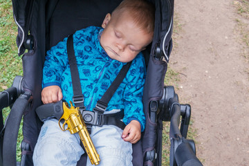 Sleeping baby with a gun in his hands