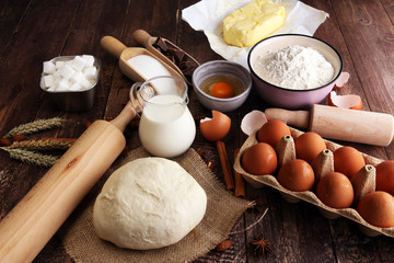 Fototapeta premium Bakery ingredients - flour, eggs, butter, sugar, yolk, almond nuts on blue table. Sweet pastry baking concept.