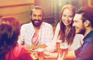 friends eating pizza with beer at restaurant