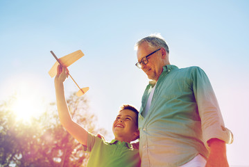 senior man and boy with toy airplane over sky