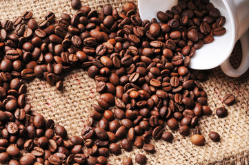 Heart shape made from spilled coffee beans from a cup on a burlap