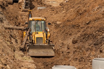 Construction of a new sewerage system. The bulldozer digs a trench for sewer pipes. Construction...