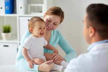 happy woman with baby and doctor at clinic