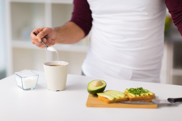 man having breakfast and adding sugar to coffee
