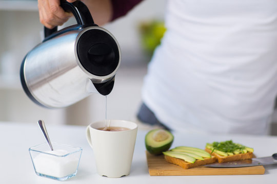 Man With Kettle Making Tea For Breakfast At Home