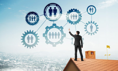 Businessman on house roof presenting teamwork and connection concept. Mixed media