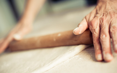 Obraz na płótnie Canvas Woman rolling dough on wooden table with wooden rolling pin