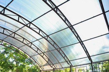A canopy made of polycarbonate arc against the blue sky. Metal construction.
