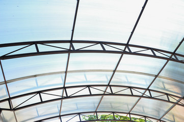 A canopy made of polycarbonate arc against the blue sky. Metal construction.
