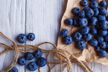 Blueberries on on craft paper, close up. Delicious berries on shabby wooden background