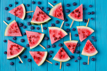 Watermelon slice popslices and blueberries on a blue wooden background. Freshness, fruits, fruity texture for design