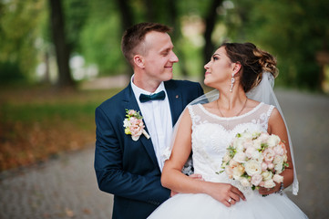 Good-looking newly married couple walking and enjoying each other's company in the park on a bright and sunny wedding day.