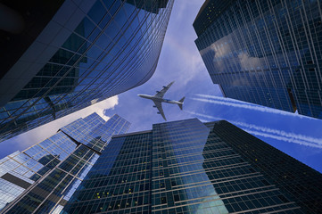 Vertical view on Moscow biggest business center Moscow City skyscrapers towers and flying passenger jet plane aircraft with trails among skyscrapers office buildings. Plane in sky among skyscrapers