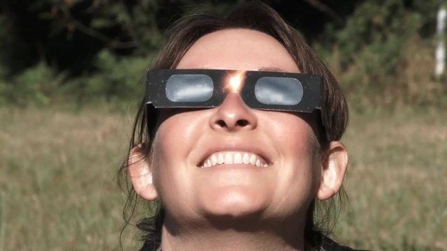 Model released woman puts on protective glasses to watch the solar eclipse.