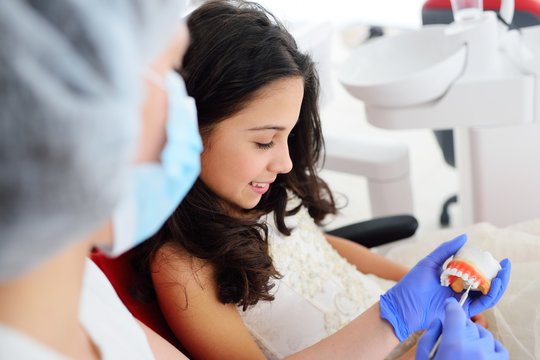 Baby girl sitting in red dental chair on examination at dentist