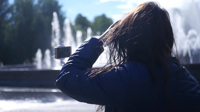 A young beautiful girl with a hair for her is photographed near the fountain. slow motion. 1920x1080. full hd