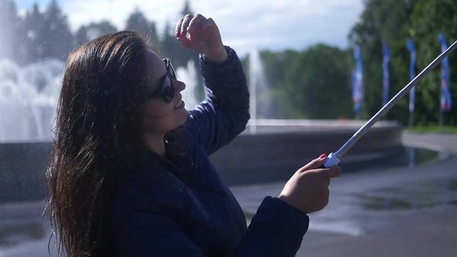 Happy girl smiling at the camera doing selfie at the fountain. slow motion. 1920x1080. full hd