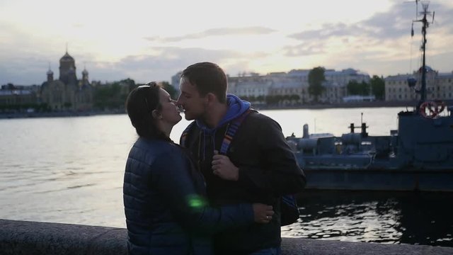 A couple in love stand on the beach near a river in the city and kiss. slow motion. 1920x1080. full hd