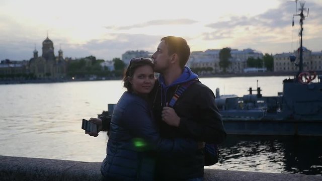 A loving couple man and woman, stand on the beach, near the river in the city and kiss. slow motion. 1920x1080. full hd